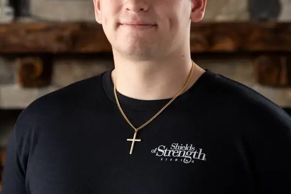 Man wearing a gold-tone Christian cross necklace from Shields of Strength